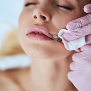 Cosmetician in latex gloves injecting the dermal filler into the woman's lips in Cincinnati OH | Clear Eyes + Aesthetics