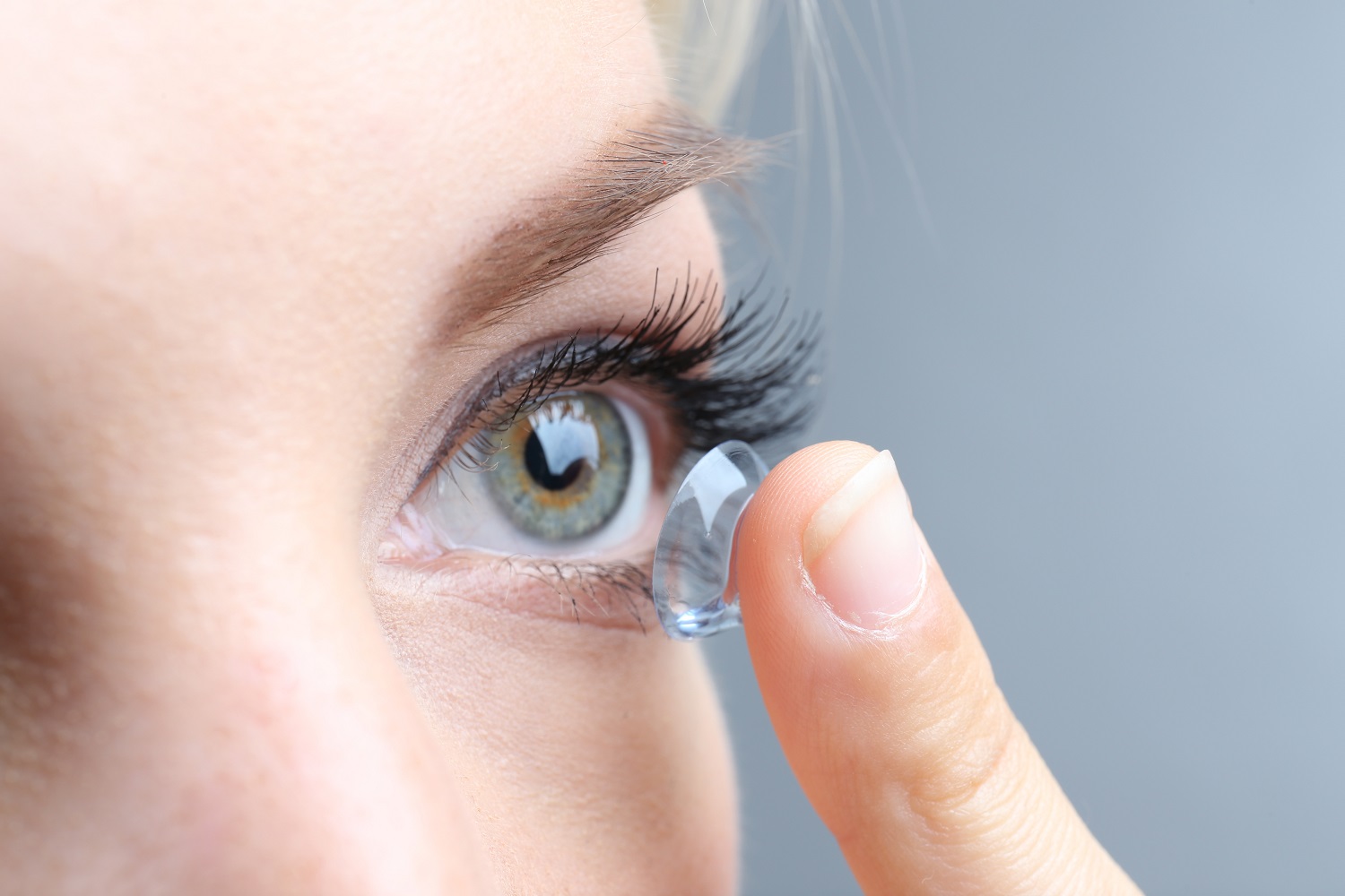 Young female applying contact lenses on her eye | Clear Eyes + Aesthetics in Cincinnati OH